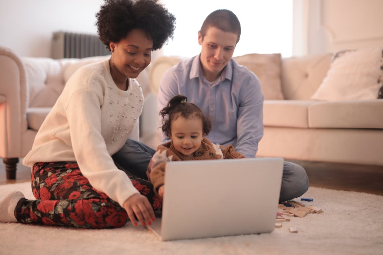 A family enjoying quality time together using a laptop in a warm and cozy living room.